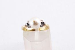 A yellow metal ring principally set with a 7.5mm pearl and finished with six single cut diamonds.