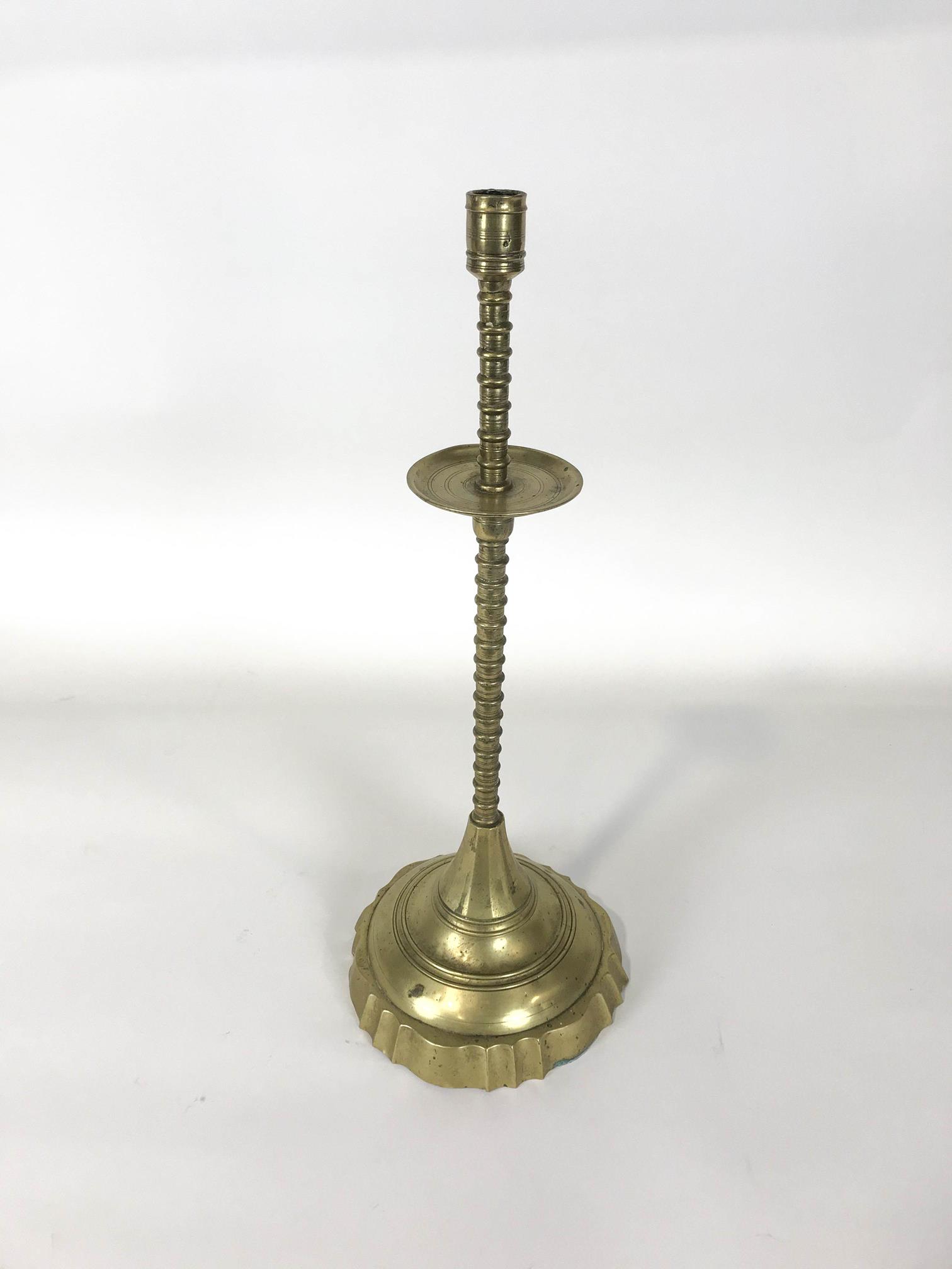 A late 18th/ early 19th century brass candlestick with flared drip pan