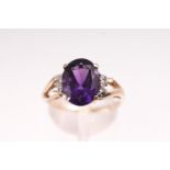 A yellow metal single stone ring set with an oval faceted cut amethyst