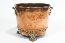 A copper coal bucket, applied with copper rivets, with cast leafy brass handles and paw feet,