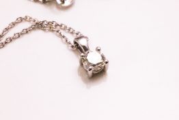 A white metal single stone pendant set with a round brilliant cut diamond