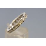 A white metal full eternity ring set with colourless synthetic spinel.