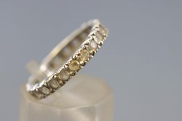 A white metal full eternity ring set with colourless synthetic spinel.