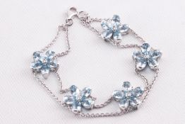 A white metal bracelet having five fixed flowers each set with pear cut aquamarines