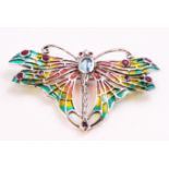 A white metal brooch stylized as a butterfly and set with a blue topaz and rubies