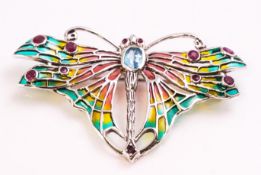 A white metal brooch stylized as a butterfly and set with a blue topaz and rubies