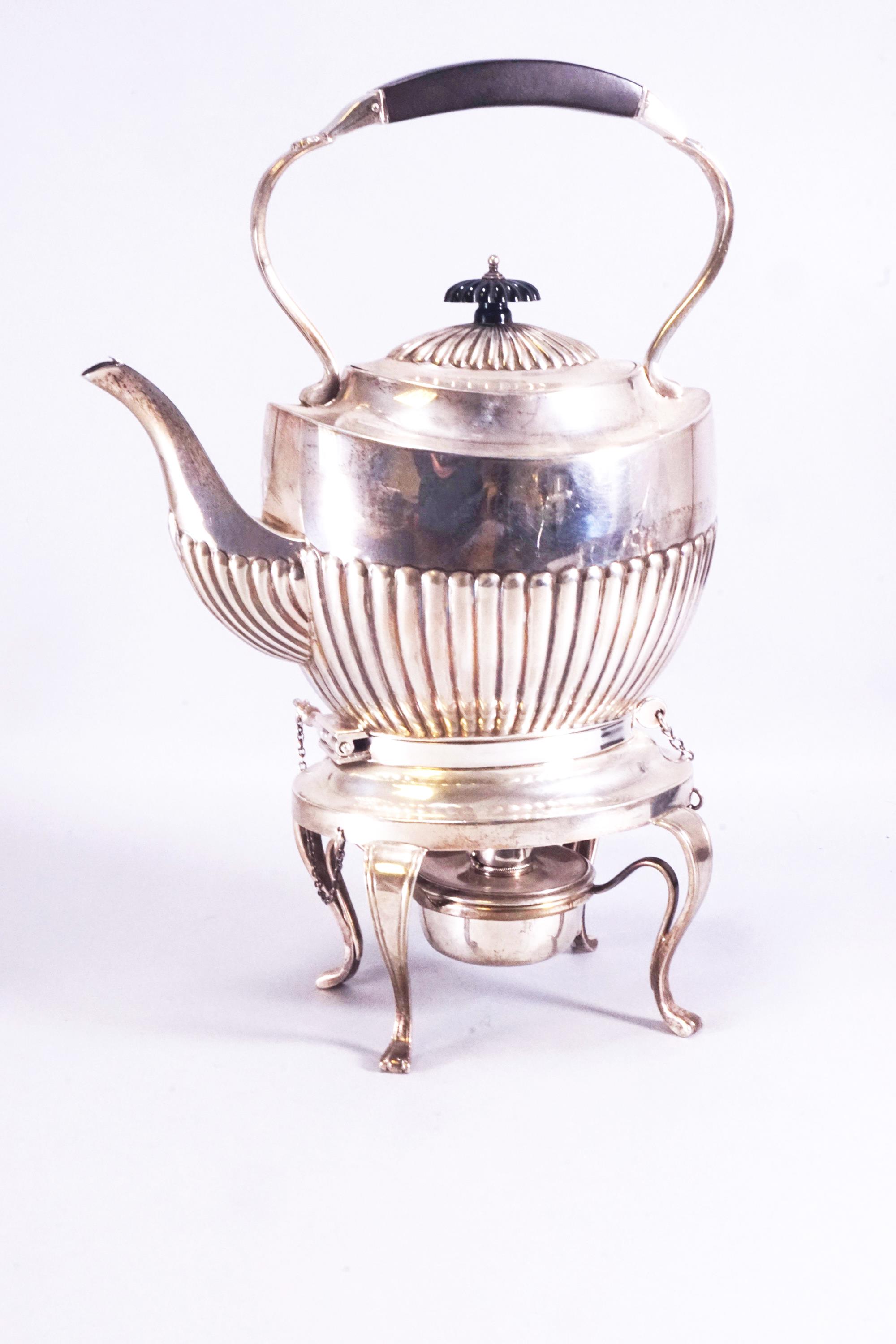 A silver spirit kettle of the usual semi-fluted oval form, on a cabriole leg burner stand,