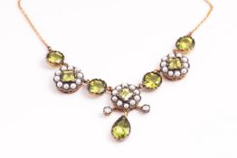 A yellow and white metal necklace having an ornate floral centrepiece design set with peridot,