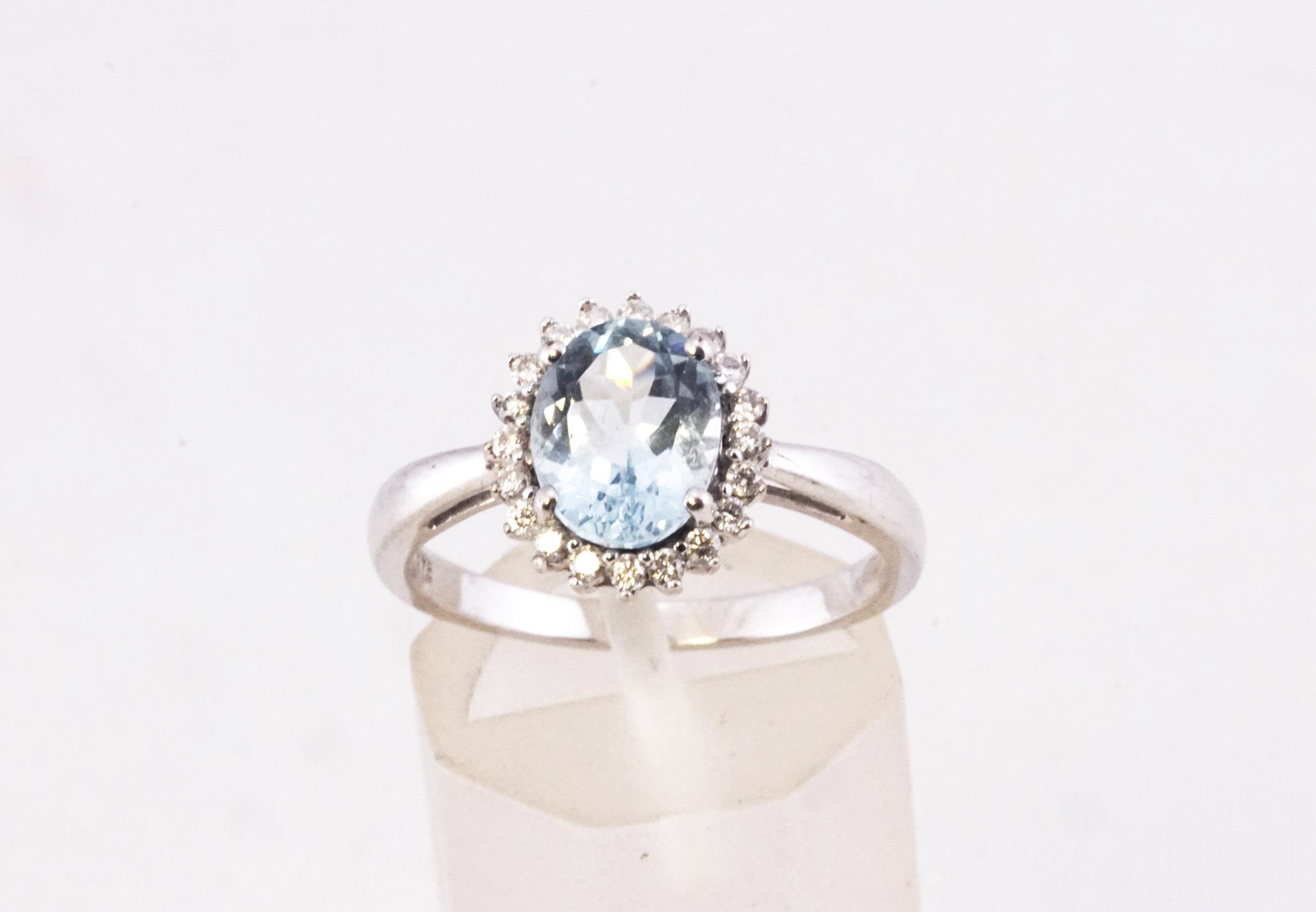 A white metal cluster ring principally set with an oval faceted cut aquamarine