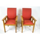 A pair of oak armchairs with red upholstery and square legs,