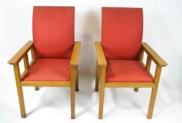 A pair of oak armchairs with red upholstery and square legs,