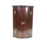 A mahogany corner cupboard, the curved hinged doors inlaid with stringing,