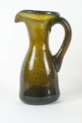 A 19th century glass jug with applied scroll handle, the concave underside with pontil mark,