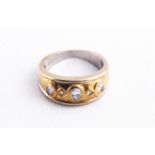 A yellow metal ring set with three oval faceted cut diamonds