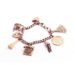 A rose gold curb link charm bracelet with padlock and safety chain having six assorted charms