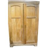 A pine wardrobe with double panelled doors, on shaped plinth base.