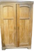 A pine wardrobe with double panelled doors, on shaped plinth base.