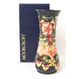 A modern Moorcroft flared baluster dark blue ground vase, decorated with pink,