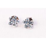 A white metal pair of floral stud earrings each set with five pear cut aquamarines