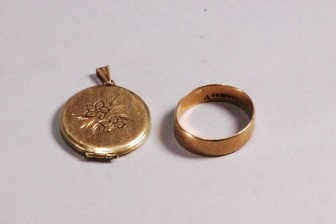 A yellow gold circular locket with floral design and a yellow gold 6.5mm flat profile wedding ring.