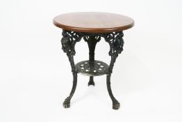 An oak topped pub table, on black painted cast iron base, moulded with classical masks,