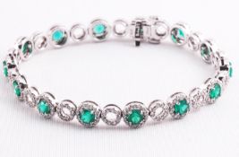 A white metal bracelet set with fourteen round faceted cut emeralds