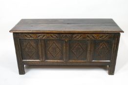 A 17th century style oak coffer with quadruple carved panelled front and frieze