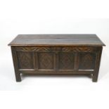 A 17th century style oak coffer with quadruple carved panelled front and frieze