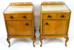 A pair of 1920's Warring and Gillows satinwood bedside cupboards with a pierced frieze