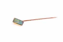 A yellow metal tie pin set with a rectangular cut opal doublet