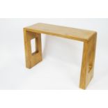 A 21st century elm console table, the flared end supports with pierced rectangles,