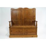 A pine box settle, of traditional form, with turned arms and panelled back,