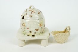 A Belleek honey pot and cover modelled as a domed basket-moulded beehive on a stand,