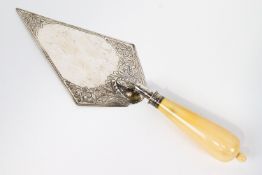 A silver and ivory presentation trowel, of usual form, the blade decorated with scroll work,