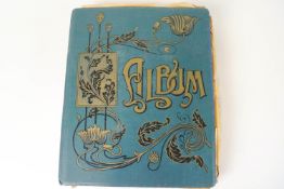 A late 19th century cloth bound card album with Art Nouveau gilt decoration to the cover