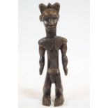 An African large carved wood fetish figure, modelled standing and carved with hatched ornament, 73.
