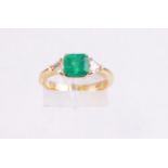 A yellow metal single stone ring set with a square step cut emerald