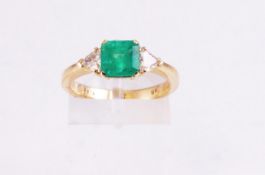 A yellow metal single stone ring set with a square step cut emerald