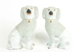 A pair of Staffordshire models of poodles, each with moulded numeral to base,