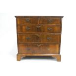 A walnut chest of drawers inlaid with cross banding,