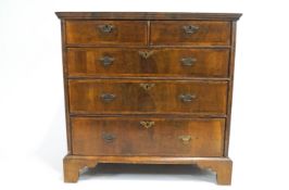 A walnut chest of drawers inlaid with cross banding,