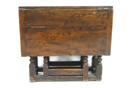 An oak gate-leg drop leaf rectangular dining table, on barley-twist legs and turned stretchers,