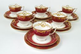 A Mintons dark pink ground part tea service with gilt borders of leafy tendrils,