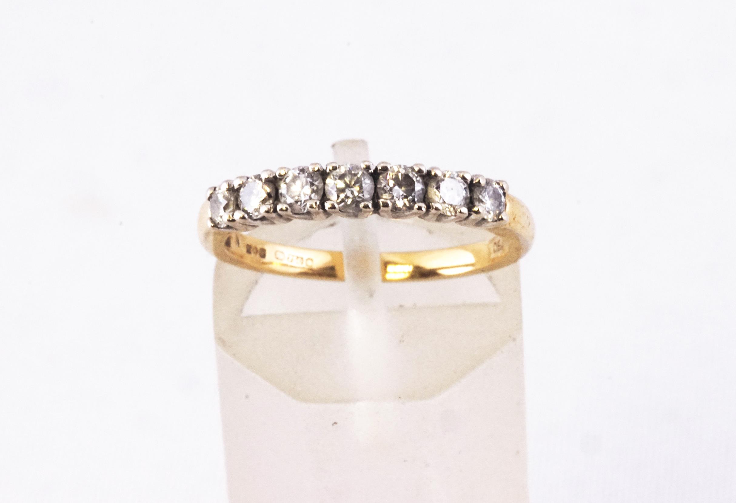 A yellow and white metal half hoop ring set with seven graduated round brilliant cut diamonds.