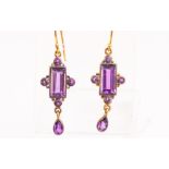 A yellow metal pair of drop earrings set with amethysts in an oxidised setting. Hook fittings.