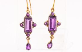 A yellow metal pair of drop earrings set with amethysts in an oxidised setting. Hook fittings.