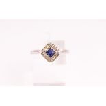 A white metal cluster ring set with a square faceted cut sapphire