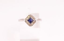 A white metal cluster ring set with a square faceted cut sapphire