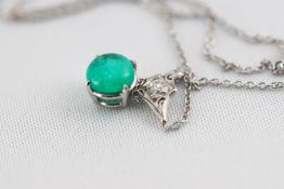 A white metal pendant set with a round cabochon cut emerald