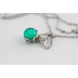 A white metal pendant set with a round cabochon cut emerald